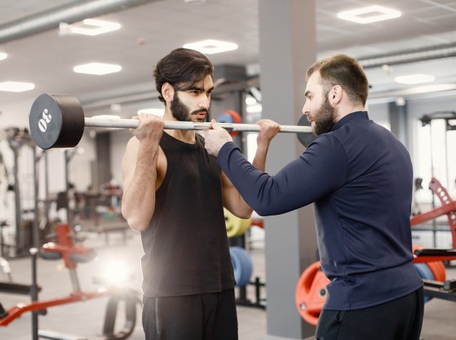 Indian man doing excercisses on special equipment at gym with pe Indian man doing excercisses on special equipment at gym with pe