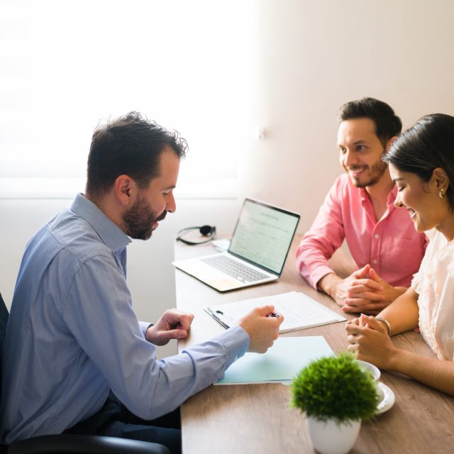 Hispanic couple buying flights with a sales agent