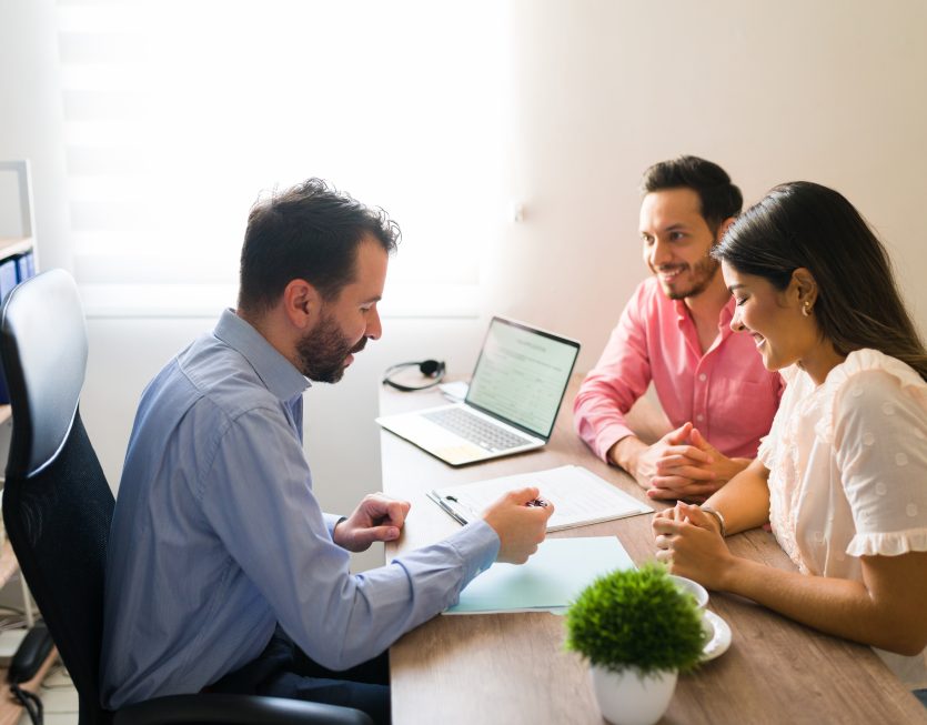 Hispanic couple buying flights with a sales agent Hispanic couple buying flights with a sales agent